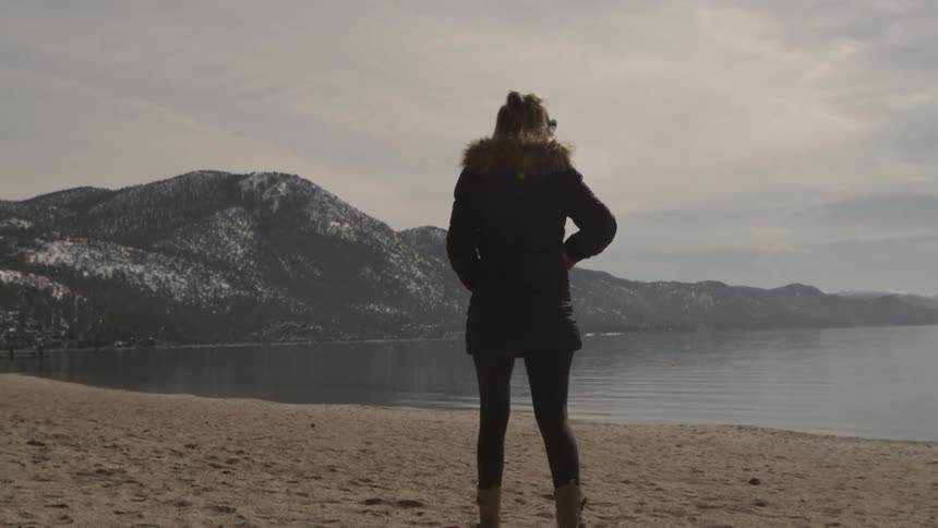 A woman is walking along the beach