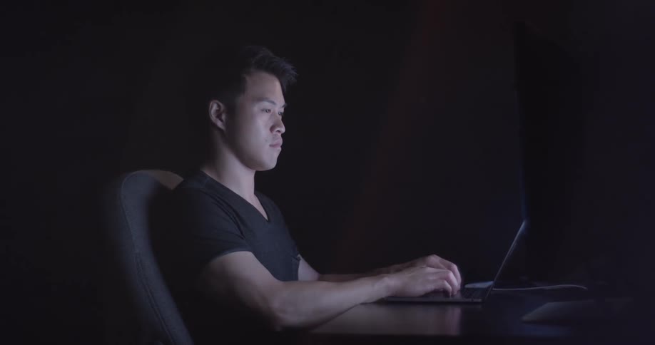 A man is typing on a laptop indoors