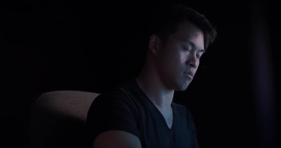 A man that is sitting in a dark office