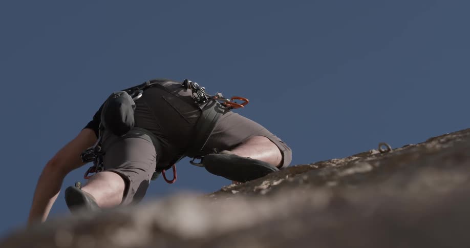 A man watching his footing while climbing high