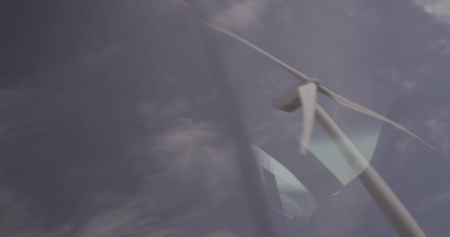 Man Driving Electric Car Through Wind Farm