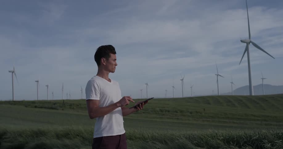 A man uses a tablet while standing in a field
