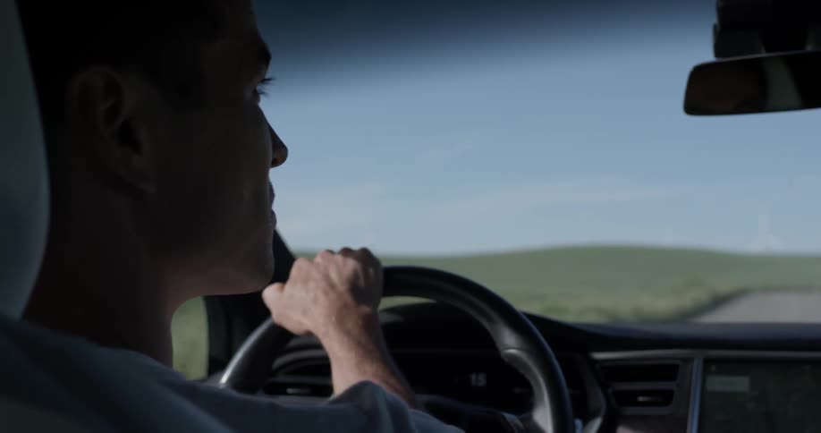 A man driving a vehicle and looking off to the side of the road