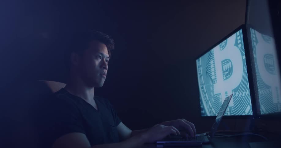 A man sits in front of his computer typing on his keyboard