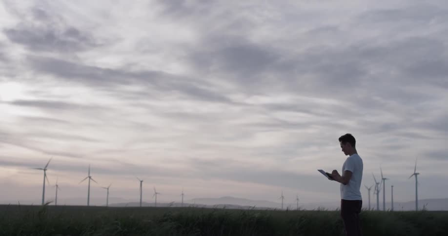 A man looking at his tablet, then up to the sky