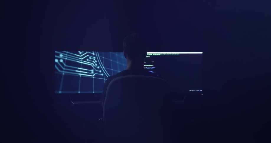 A man watches two monitor displays in front of him
