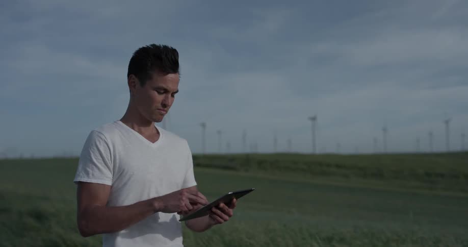 A man tapping on a tablet outside in the wind