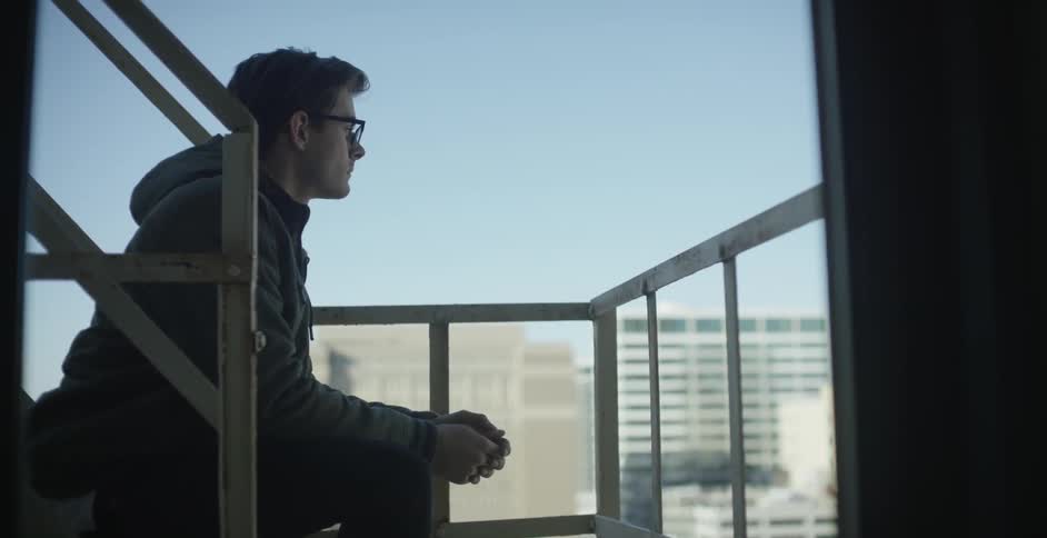 A man sits on the steps looking over the city