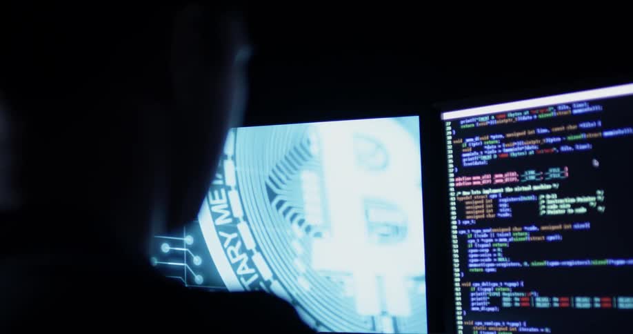 Man sits at desk with several monitors in the dark