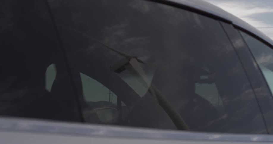 Windmill reflection on car window as door closes
