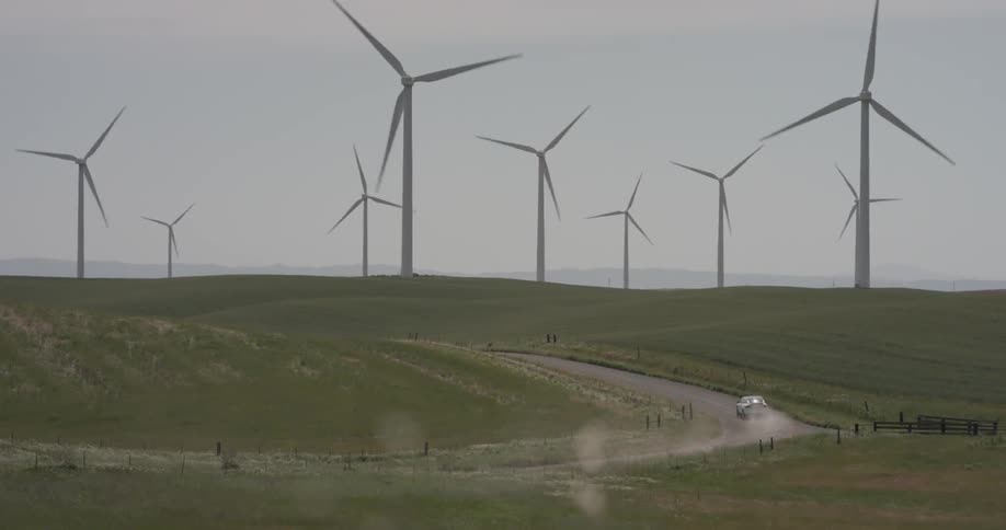 Man Driving Electric Car Through Wind Farm