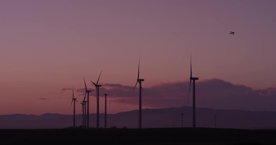 Man Driving Electric Car Through Wind Farm