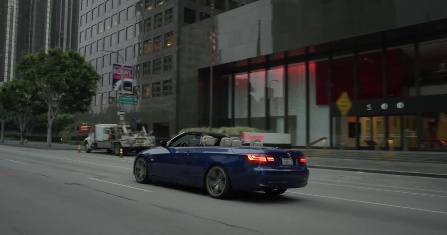 A blue convertible driving down a city