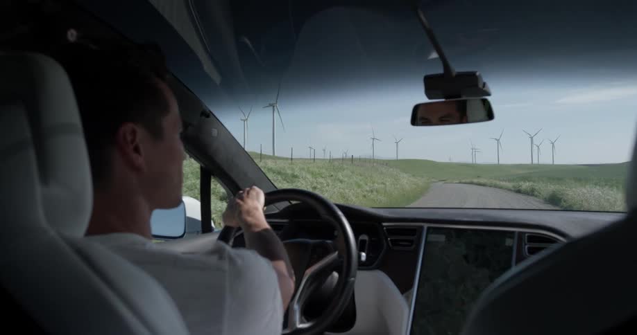 A man driving is looking out the side window