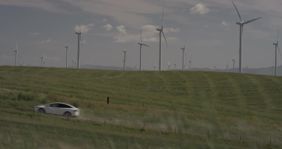 A car driving around in a field of windmills