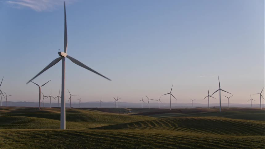 Windmills on a wind farm spin around in the sunshine