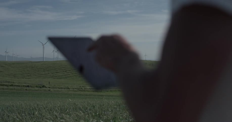 Man Driving Electric Car Through Wind Farm