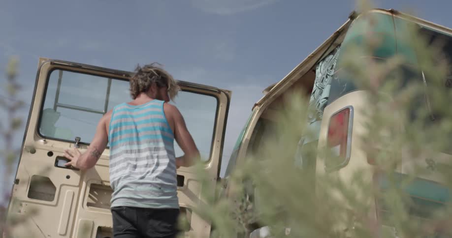 A man walking around to the back of a van and opening the door