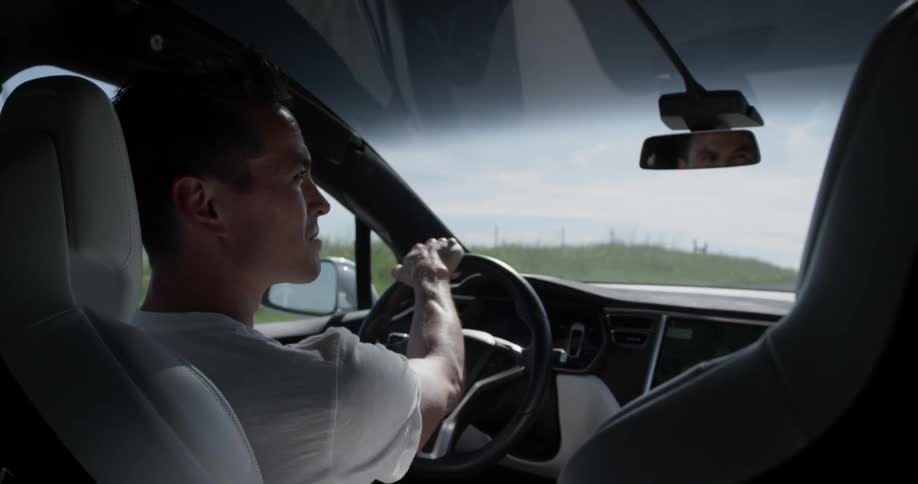 Man Driving Electric Car Through Wind Farm