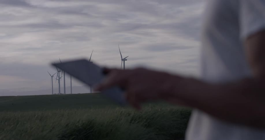 A man that is using a tablet while standing in a field
