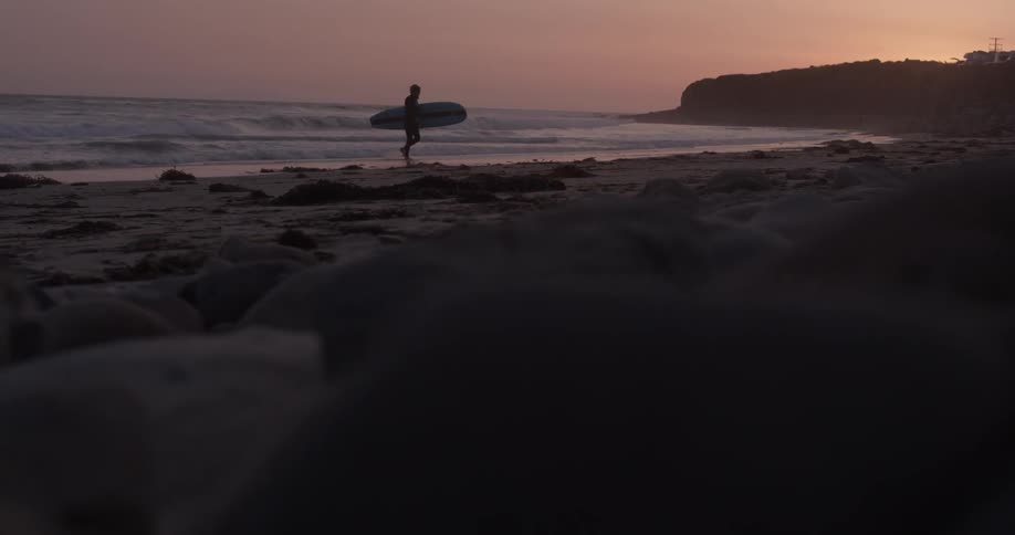 A person is carrying a surfboard out of the water
