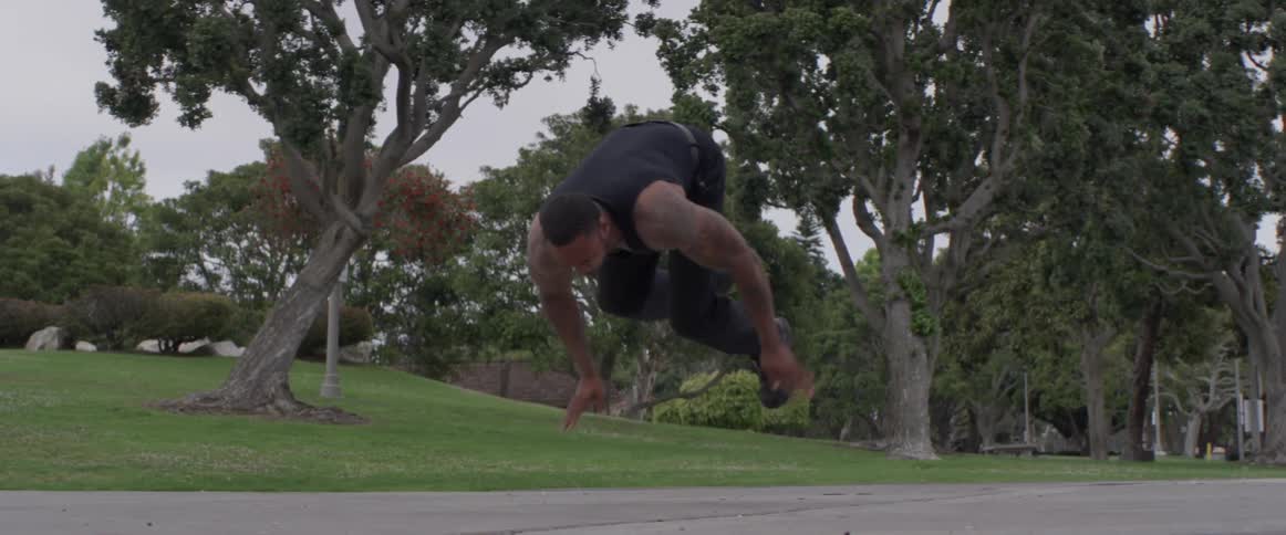 A man is doing push ups on a walking path and pushes himself into the air