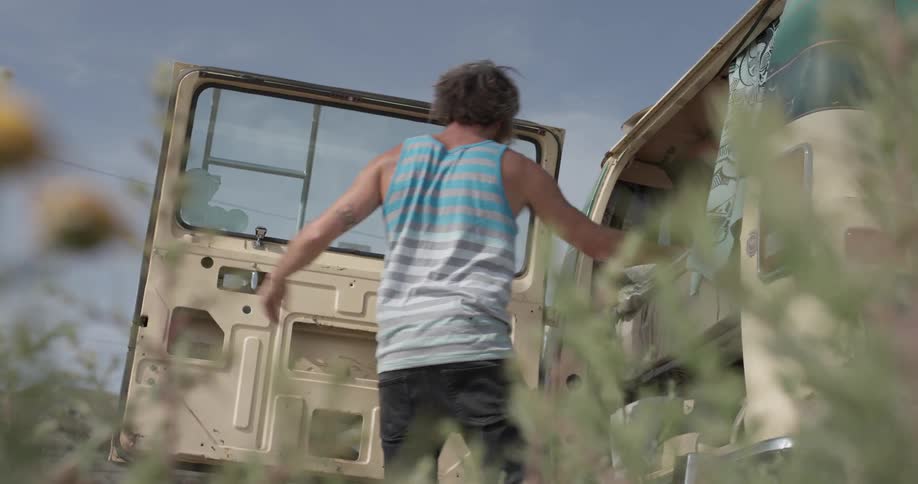 A man folding clothes and then putting them in the back of a van and then closing the door