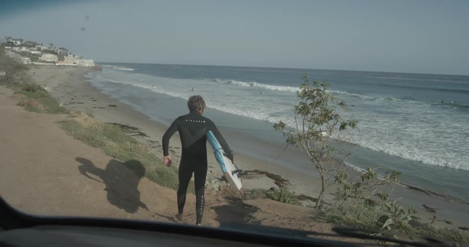 A man carrying a surfboard down to the beach