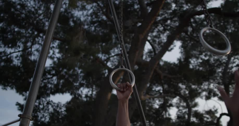 A man reaches up to grab gymnast rings