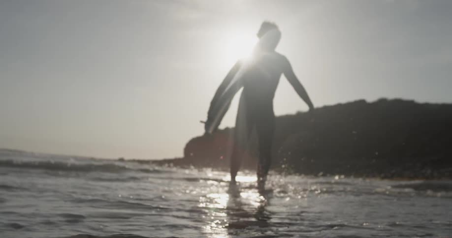 A man that is walking at the edge of the ocean