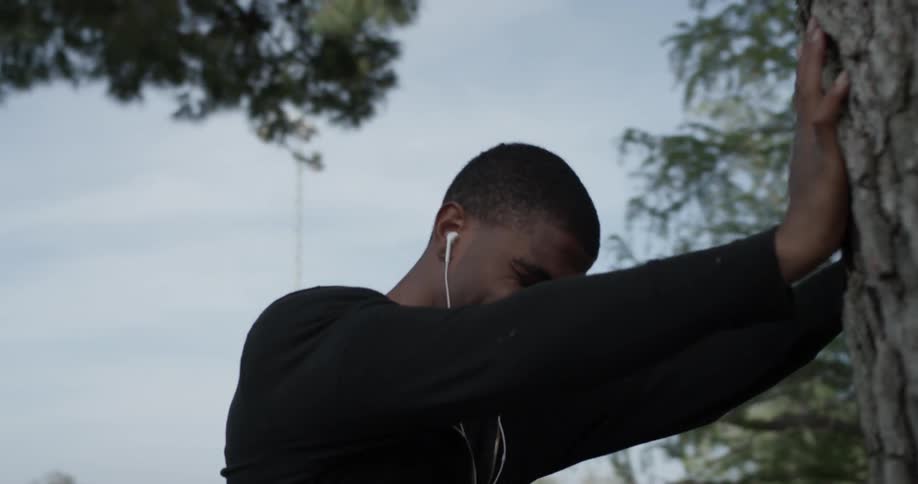 A man leaning against a tree outside