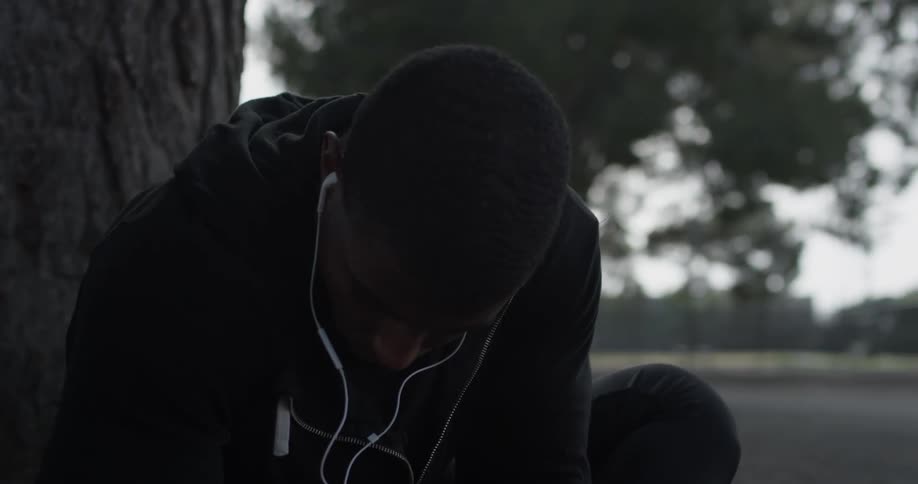 A man stretches outside under a tree