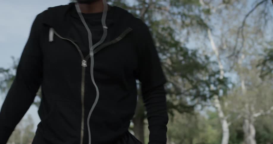 Man wearing earphones stretches outdoors on a sunny day