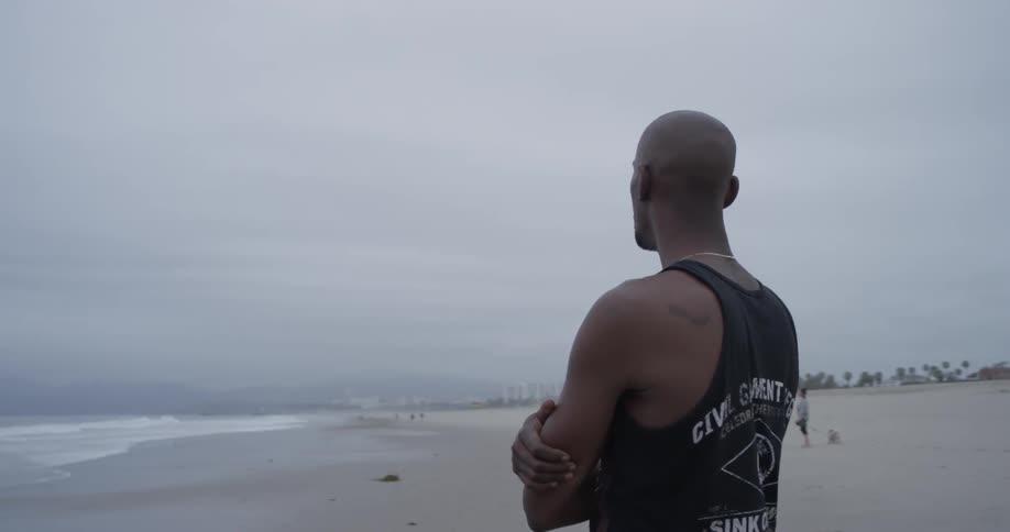 A man standing at the beach with his arms crossed