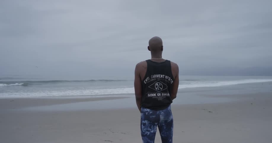 A man claps his hands while looking at the ocean
