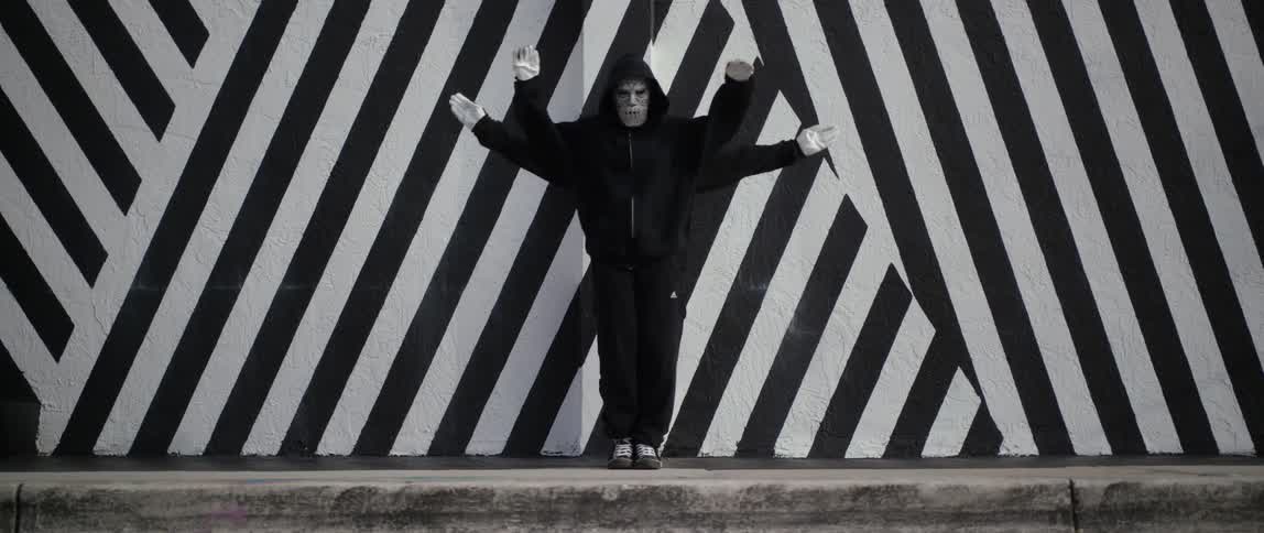 Two dancers dancing as one in front of a striped wall jump apart and walk off
