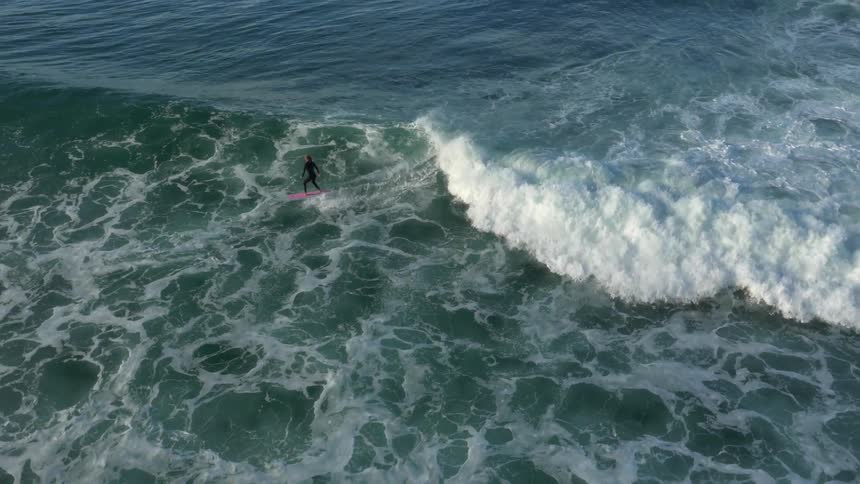 Lone surfer riding some waves towards the beach