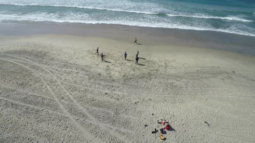A group of people playing volleyball on a beach