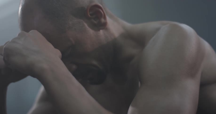 A man kneels down and puts his hand to his face