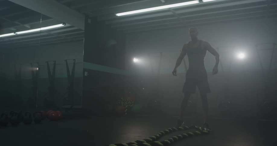 A man shaking two large ropes