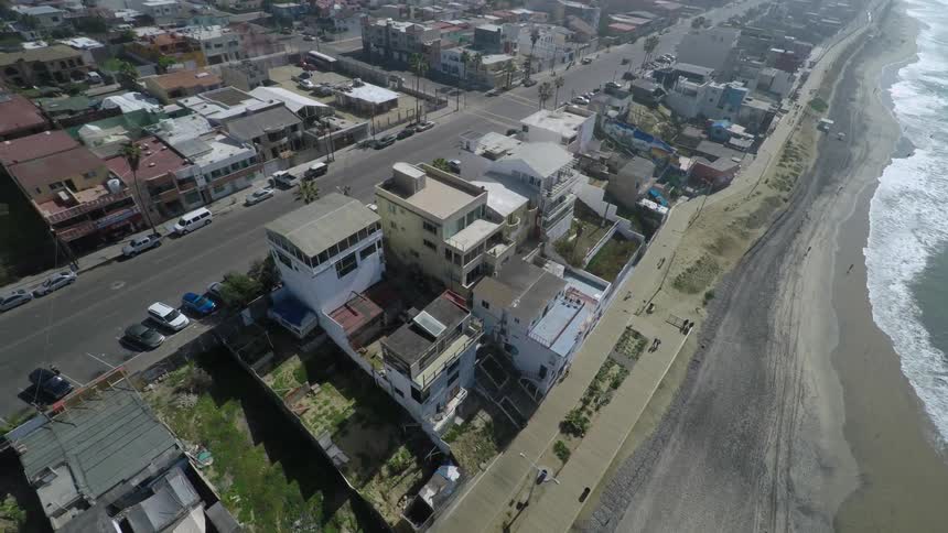 Aerial view of homes along the shoreline as waves roll onshore