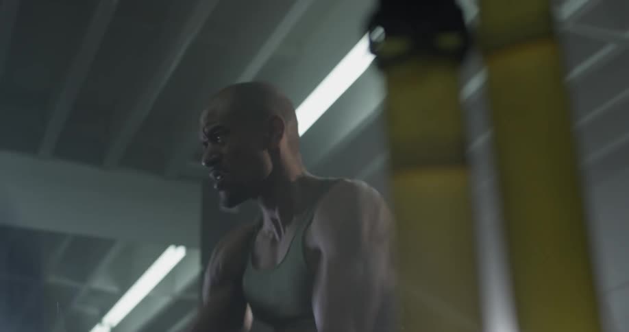 A man exercises in a gym with large ropes