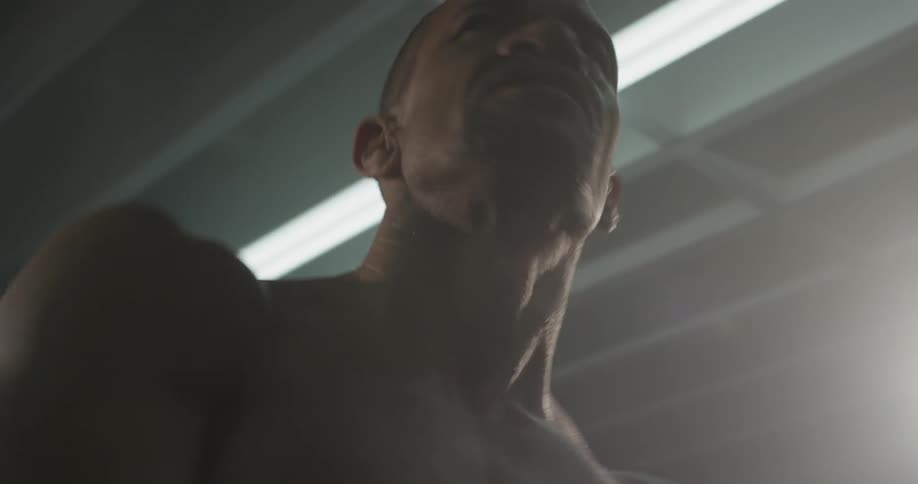 A man with no shirt on stretching in a gym