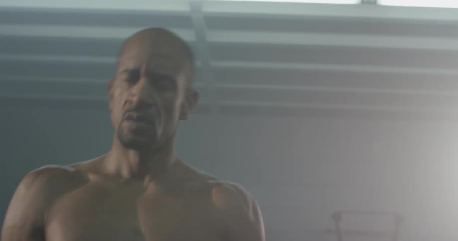 Man jumps up and down and shakes muscles at gym