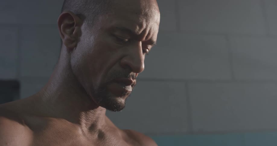 A man with no shirt on looking down at the ground