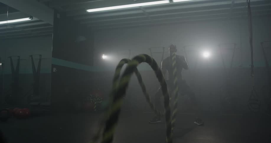 A man sends waves down two ropes by whipping them up and down