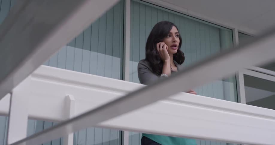 A woman talking on a phone on a balcony