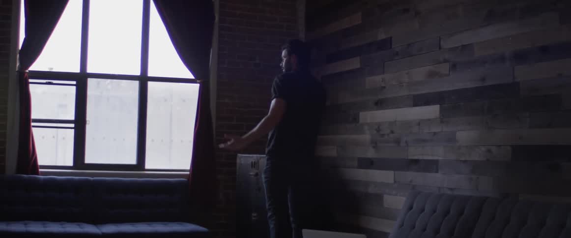 A man setting his laptop on a coffee table and getting up
