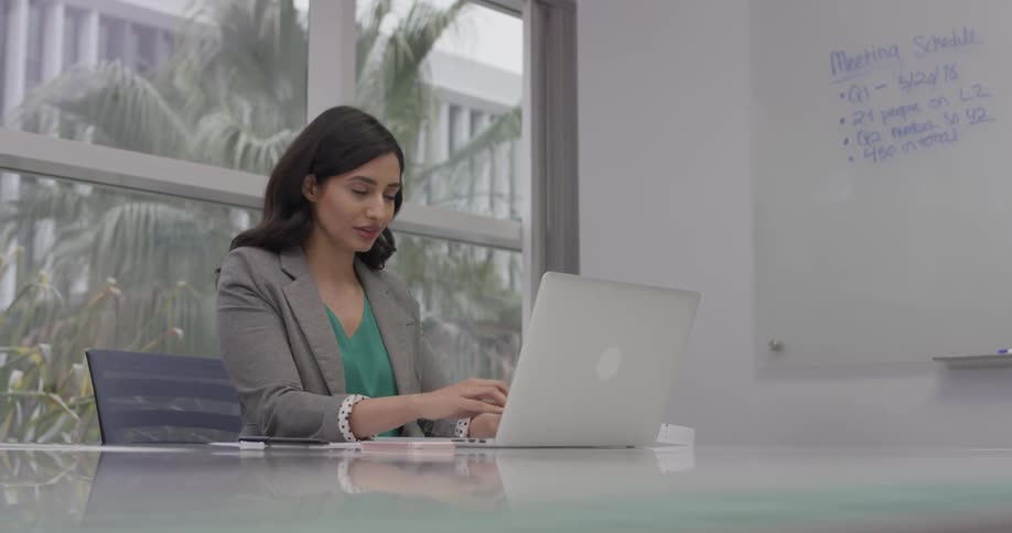 A woman checking her notes as she types on a computer