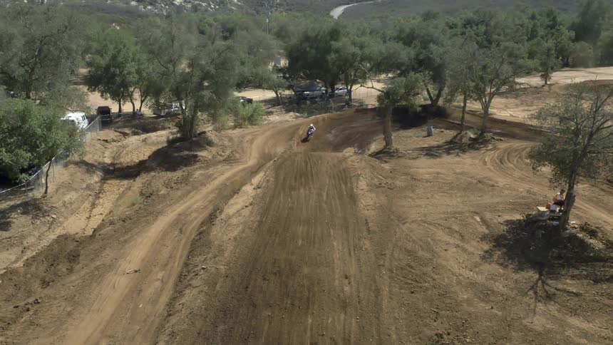 A person riding a motorcycle races and jumps around a dirt track